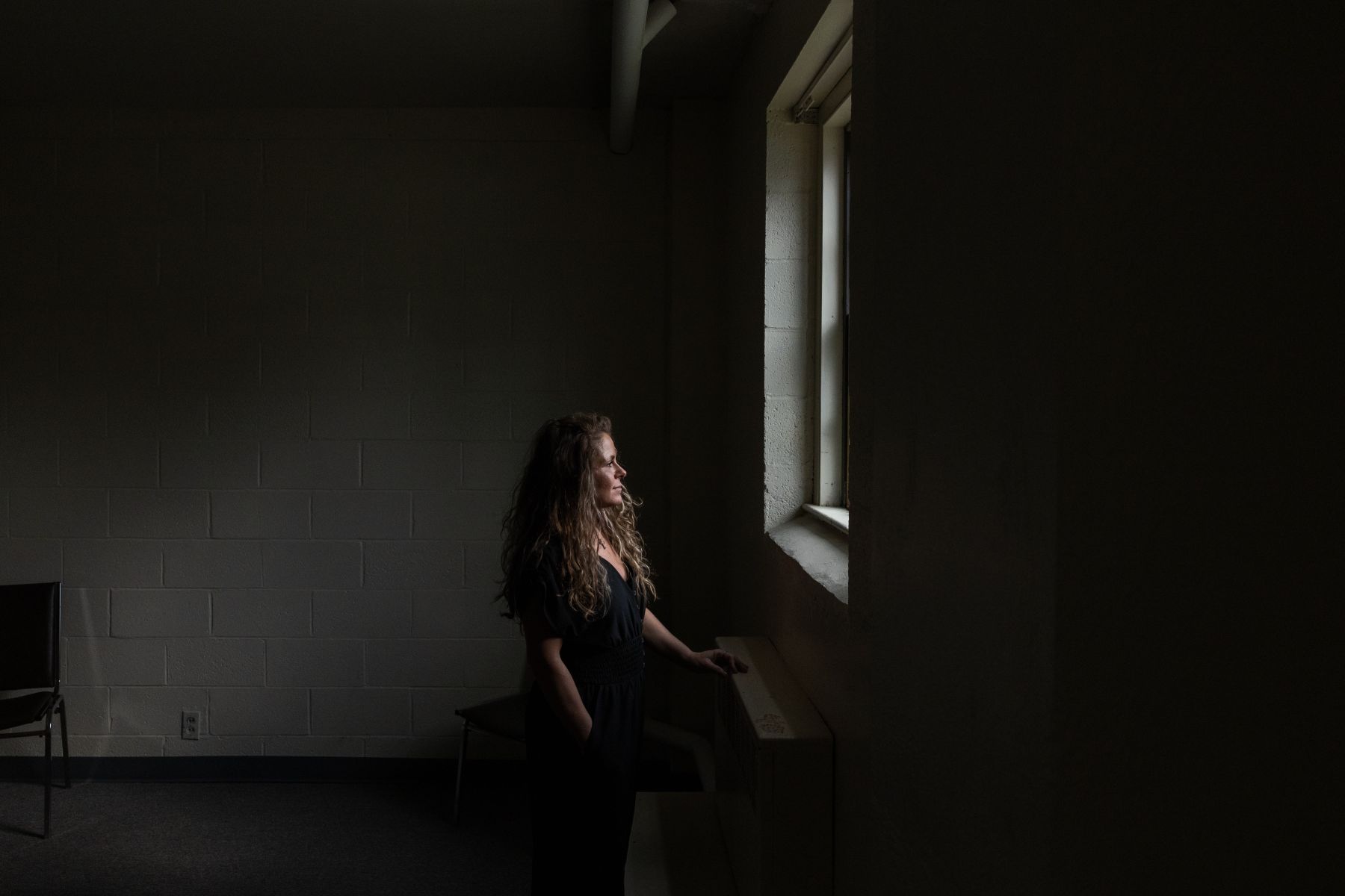 Audrey Condon looks out a window in a dark room.
