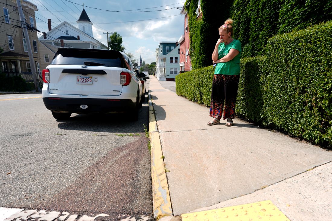 A woman looks at the ground standing near the scene of the ice shooting in biddeford.