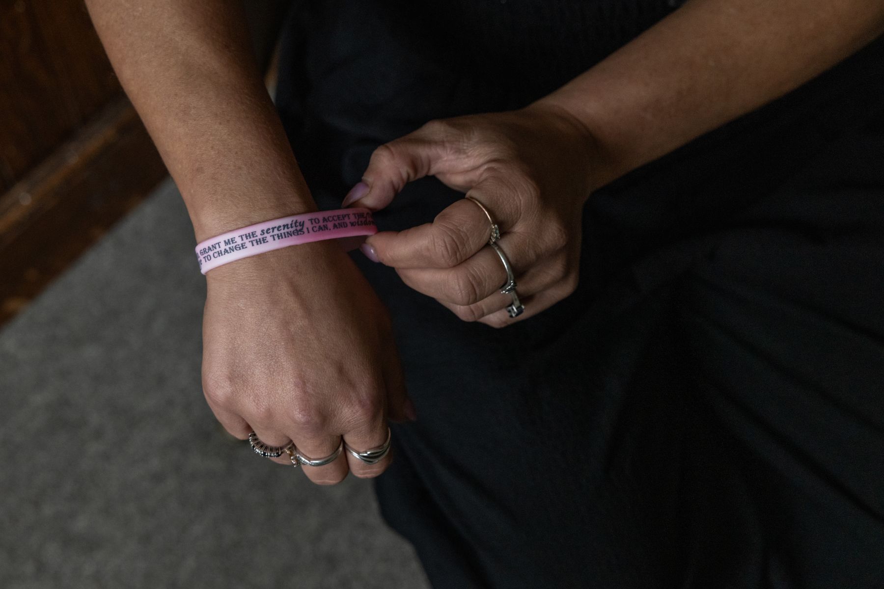 a woman's hand tugs on a silicone bracelet she is wearing
