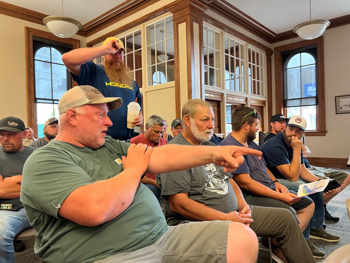 a crowd of people, mostly seated, at the council meeting.