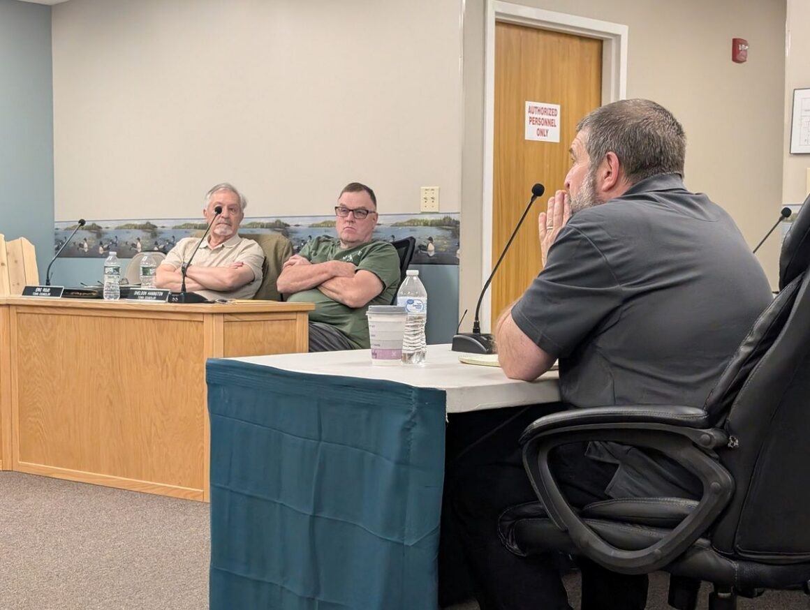 Two councilors listen to the Lincoln town manager speak during a meeting.