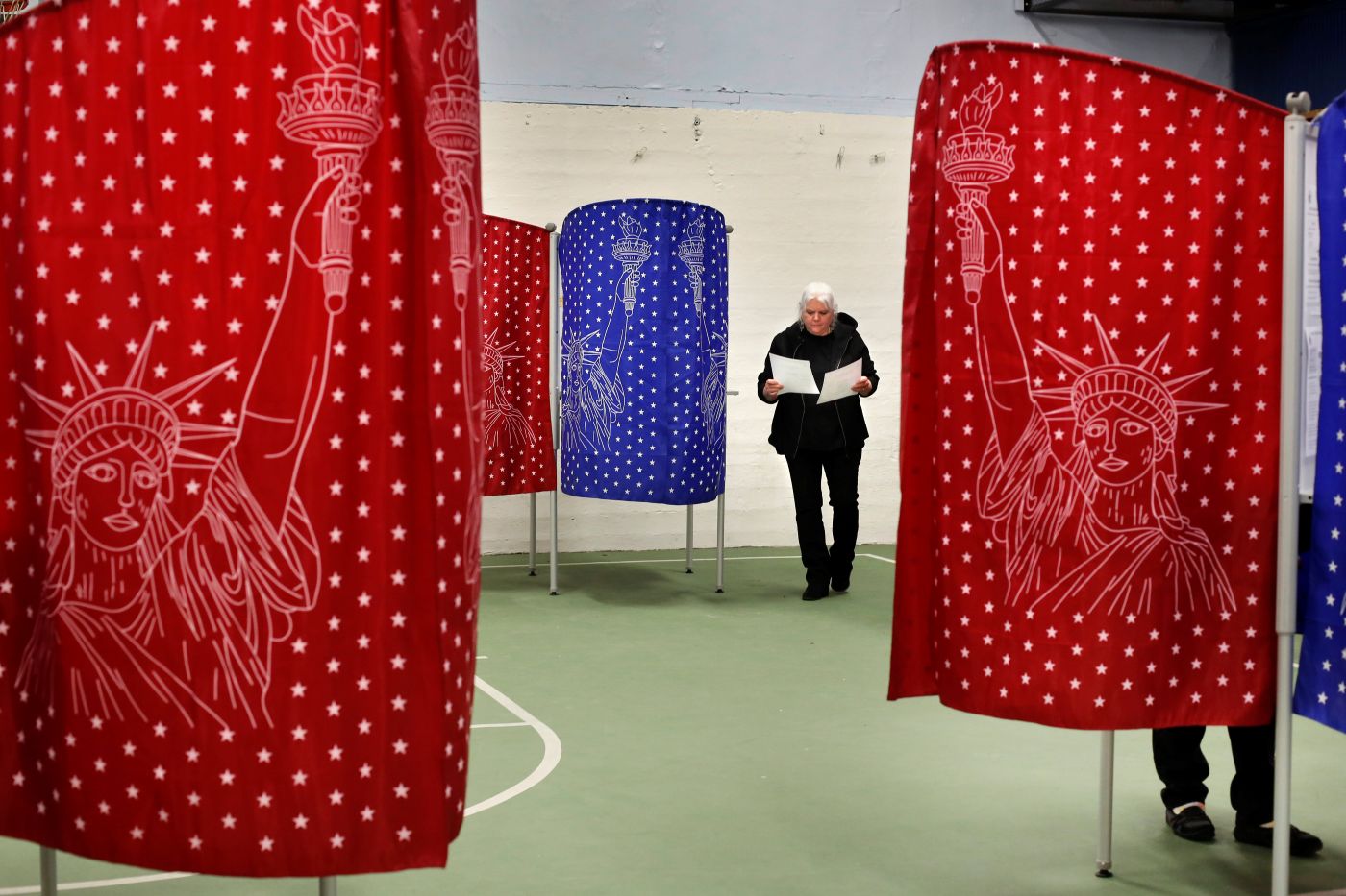 a woman looking at a ballot in each of her hands.