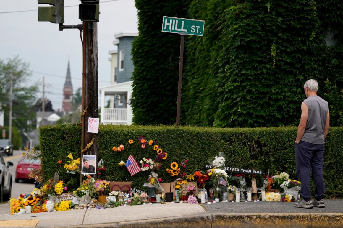 a man stands next to a makeshift memorial in biddeford
