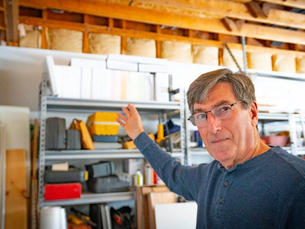 Harry Sanborn gestures to items on shelving.