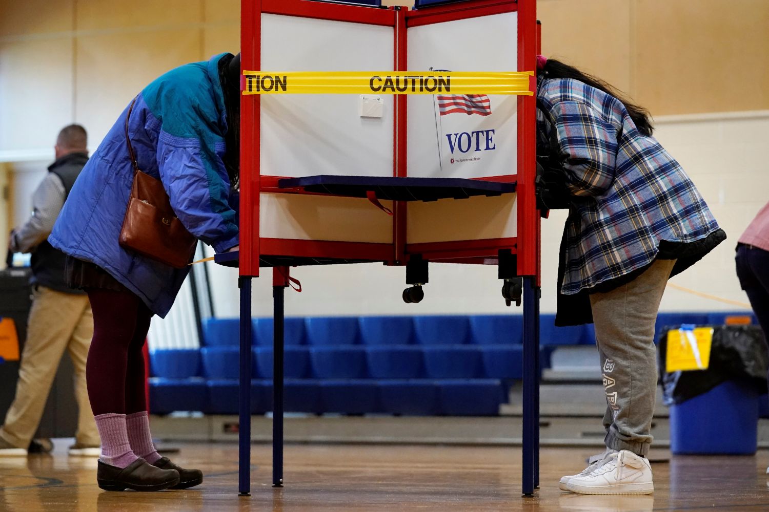 two voters stand while completing their ballots.