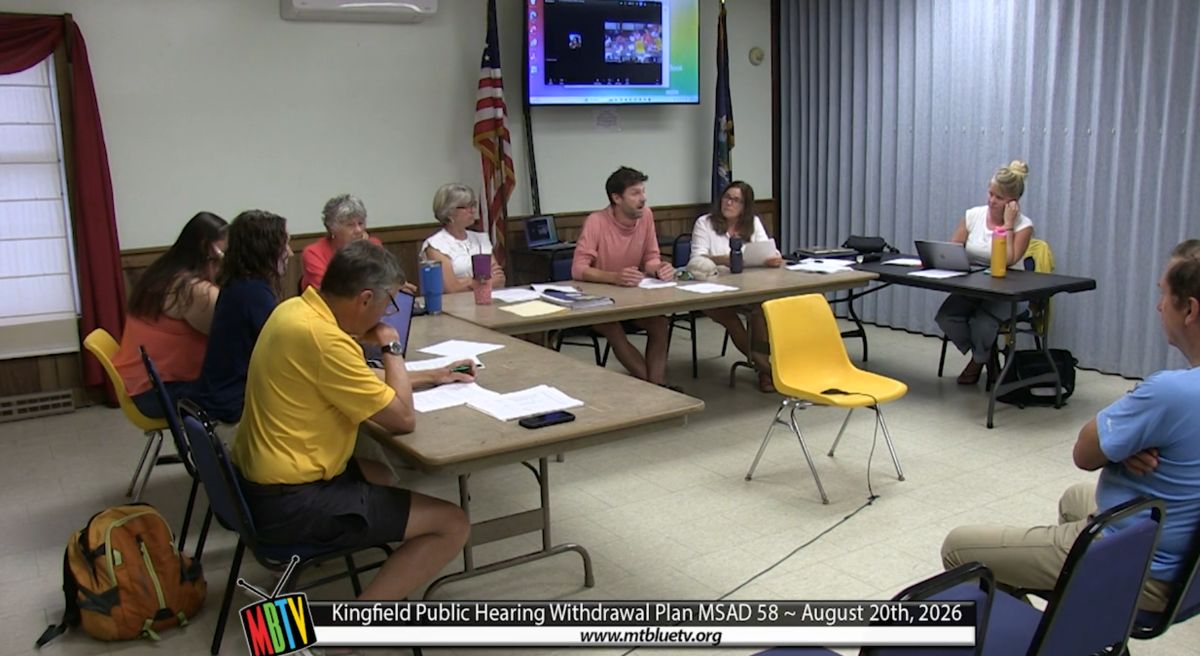 members of the committee gather around a table during the meeting.
