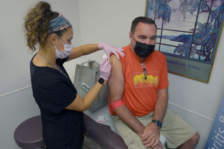 a man receives a vaccine shot in his arm