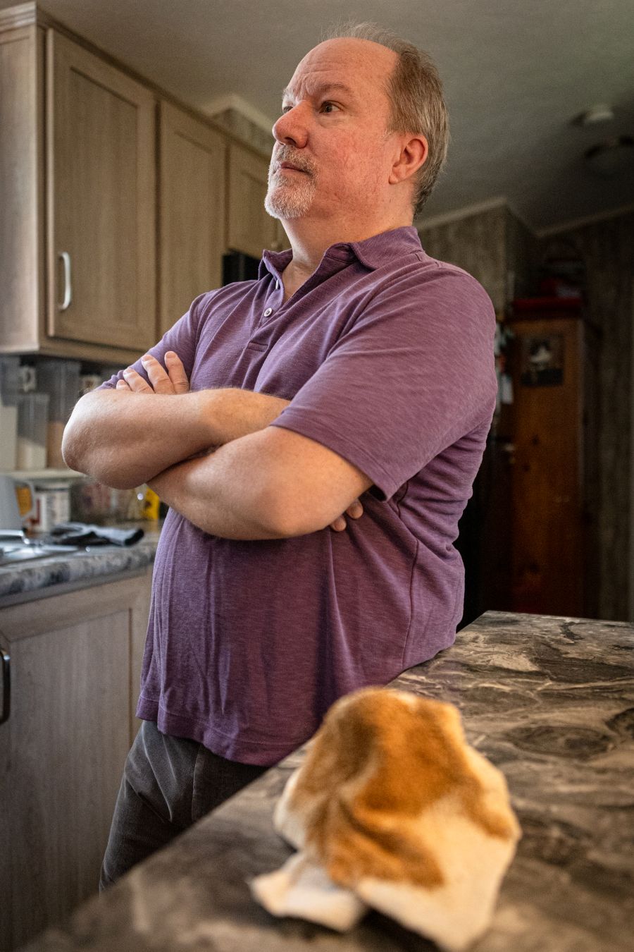 a man stands with his arms crossed. a rag covered in brown water sits on a counter next to him.