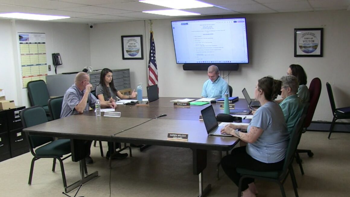 members of the select board sit around a table.