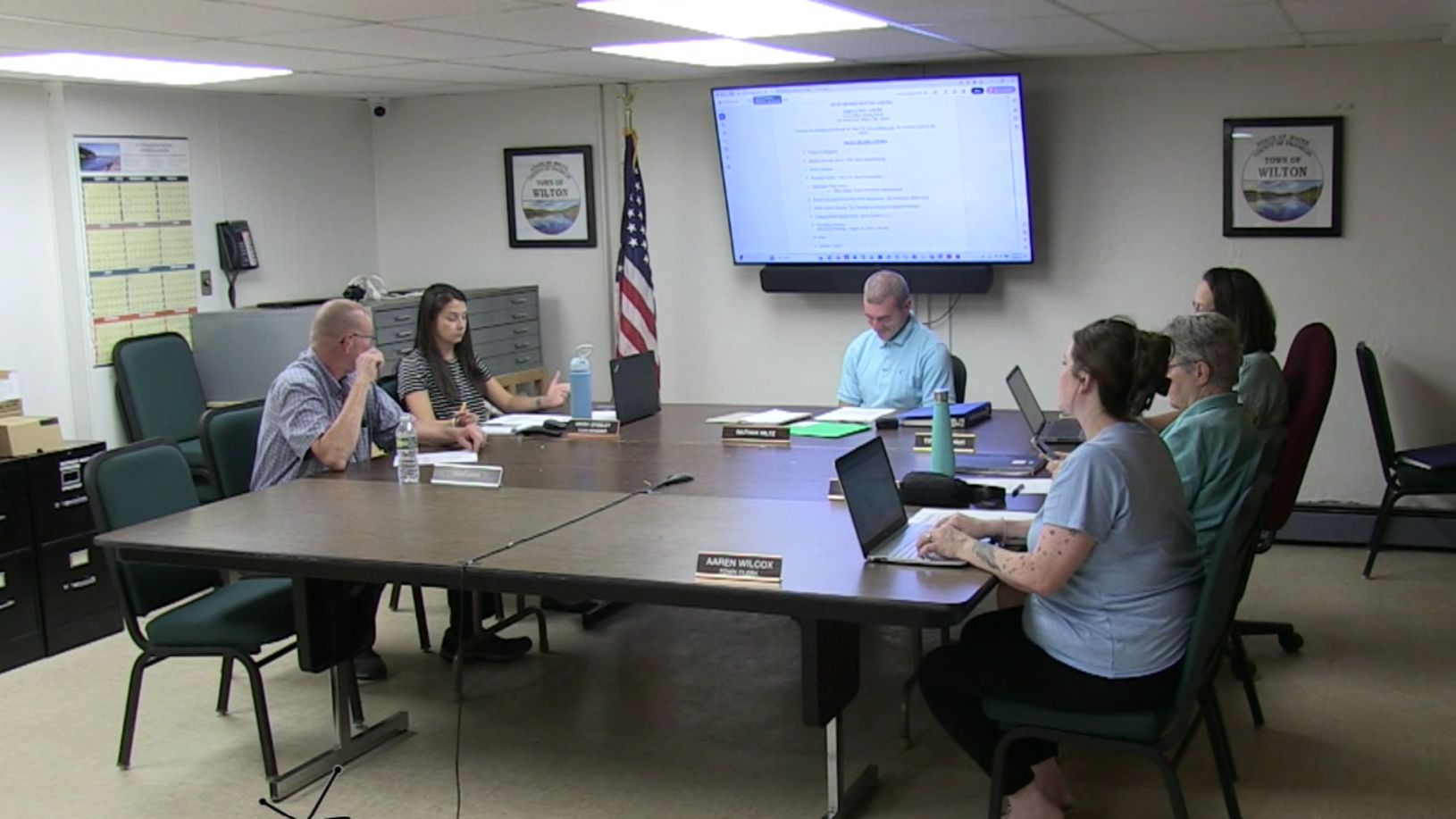 members of the select board sit around a table.