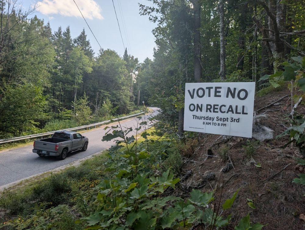 car drives by a sign that says vote no on recall.