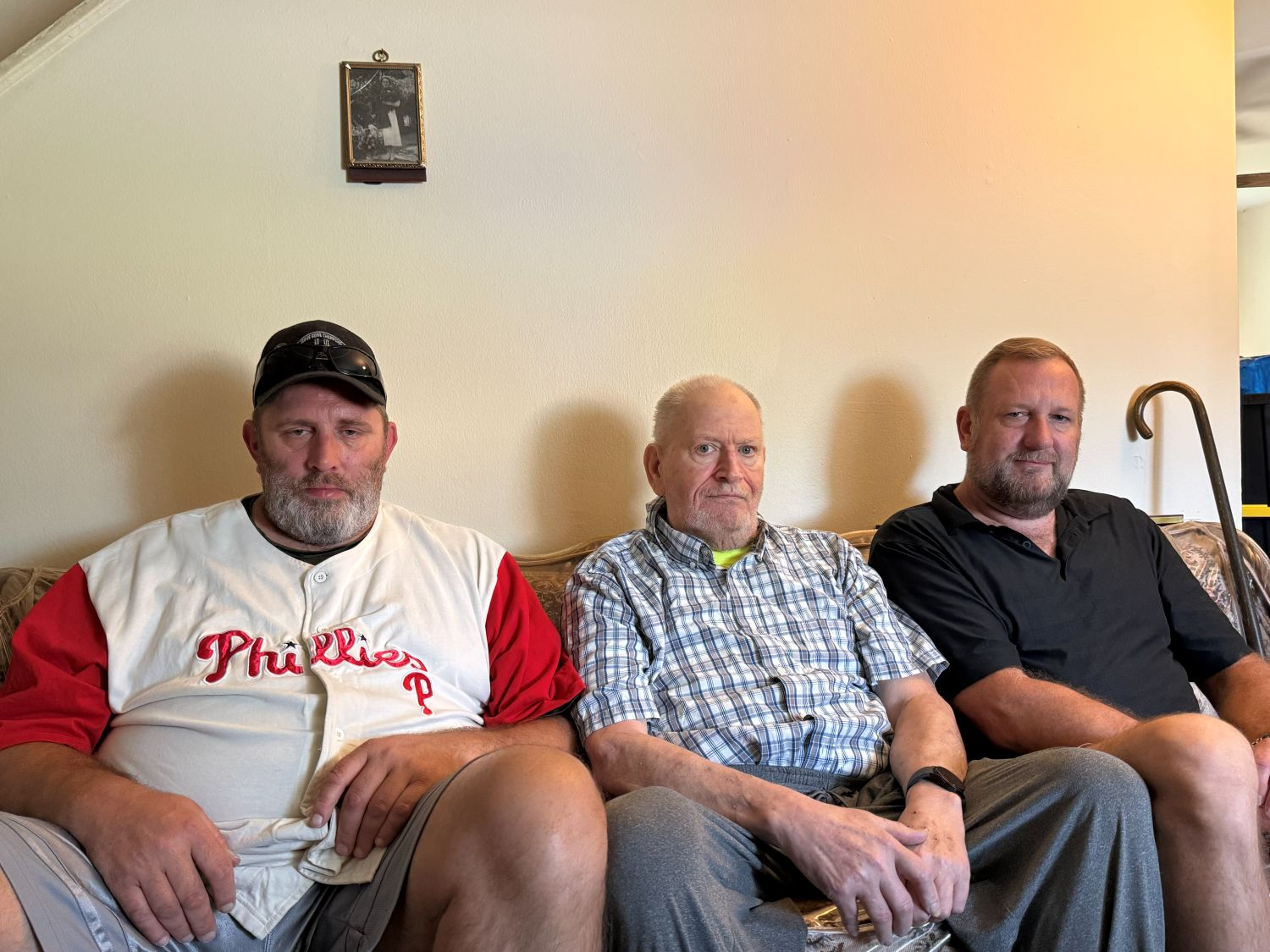 three men pose for a photo while sitting on a couch
