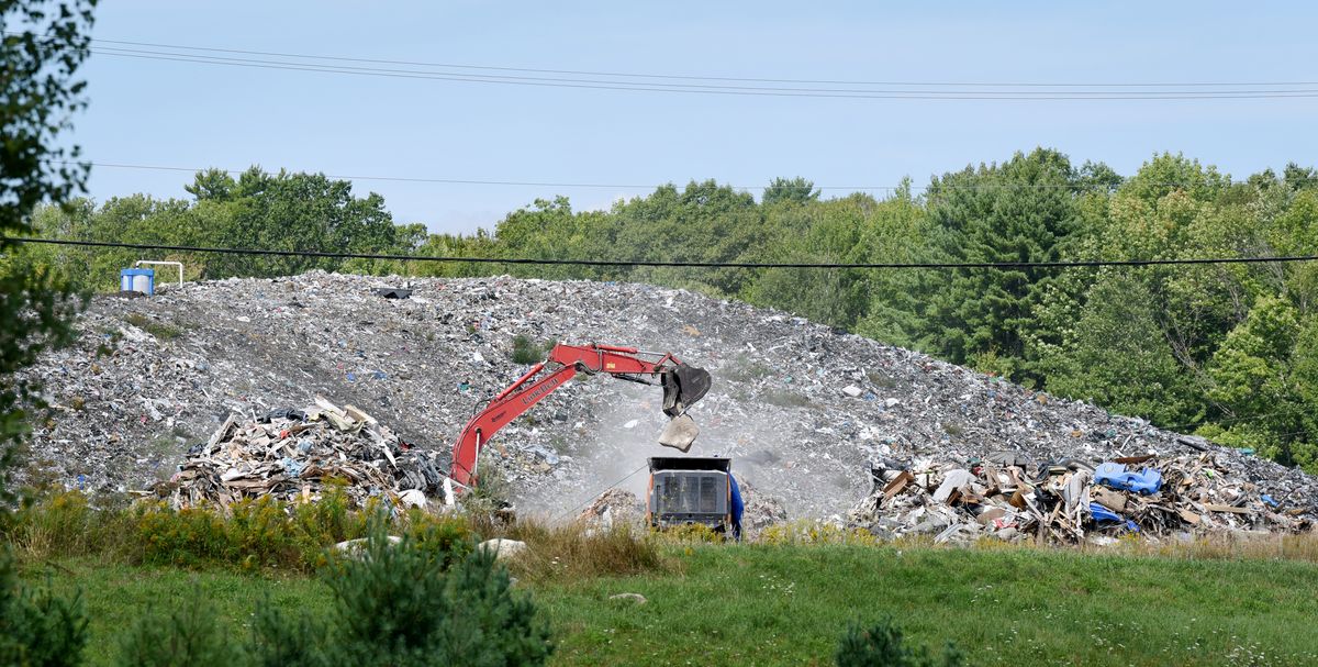 excavator lifts waste at landfill