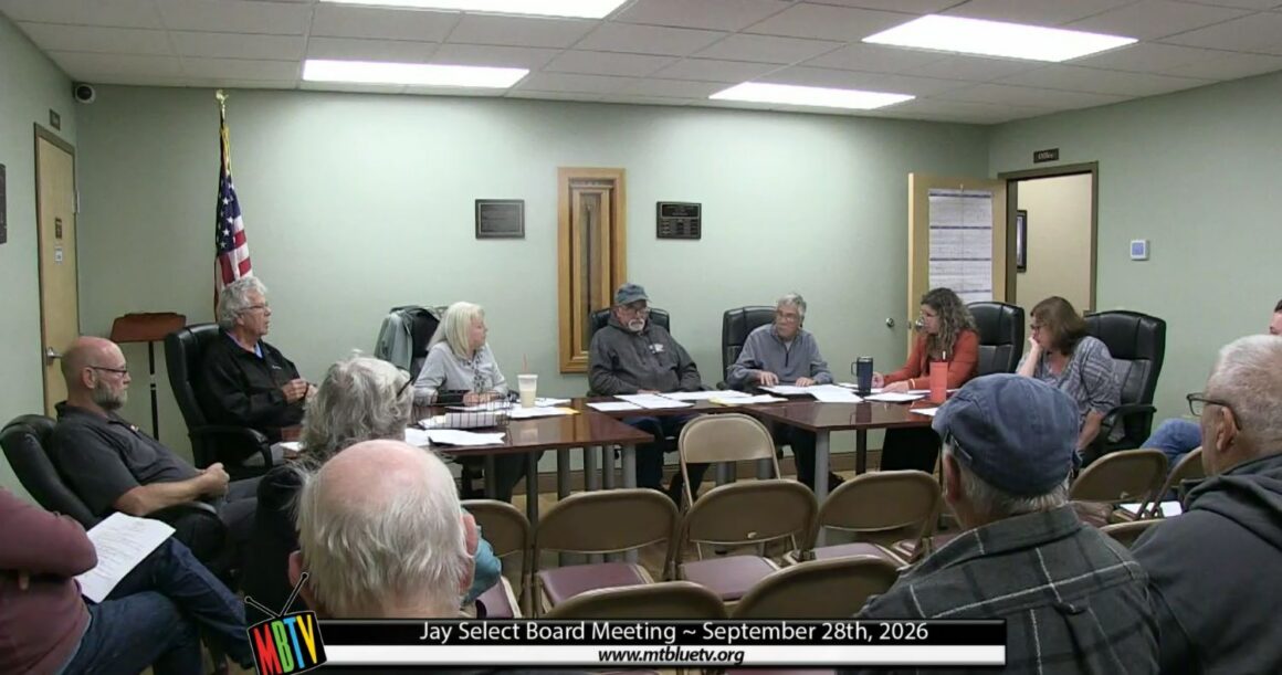 select board members gather around a meeting table.