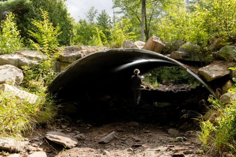 a woman walking through a dry river tunnel.