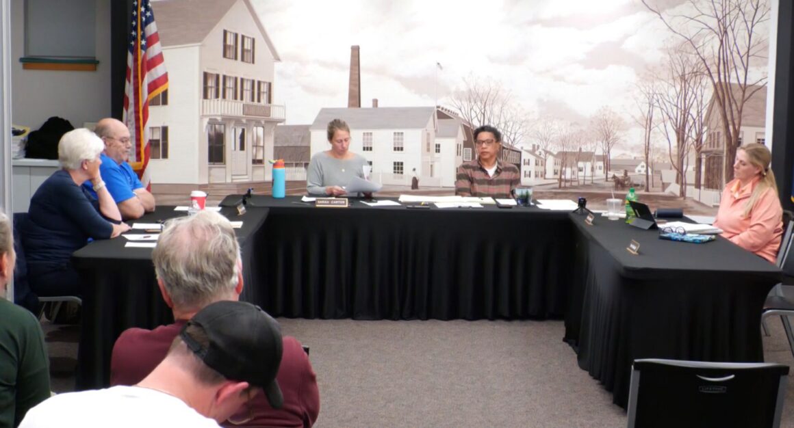 select board members sit around a u-shaped table.