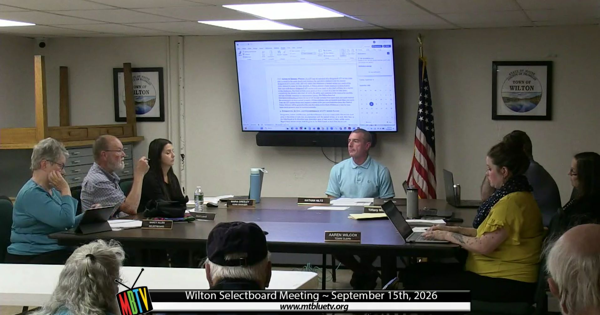 members of the board sit around a table during a meeting.