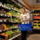 a woman placing a vegetable into her shopping basket