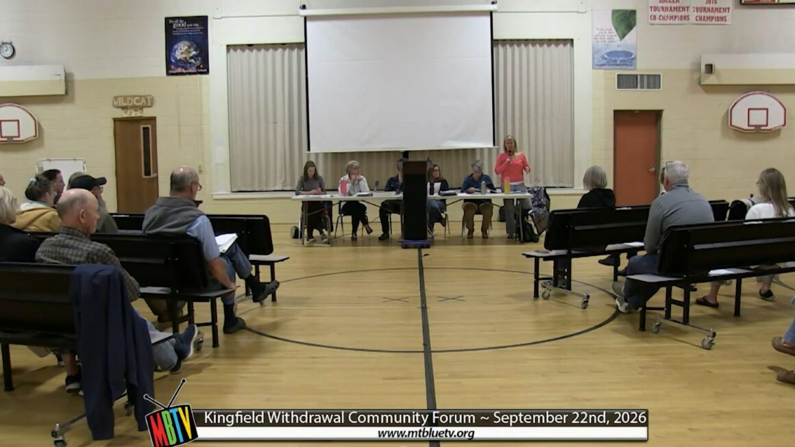 a committee member stands while addressing the crowd