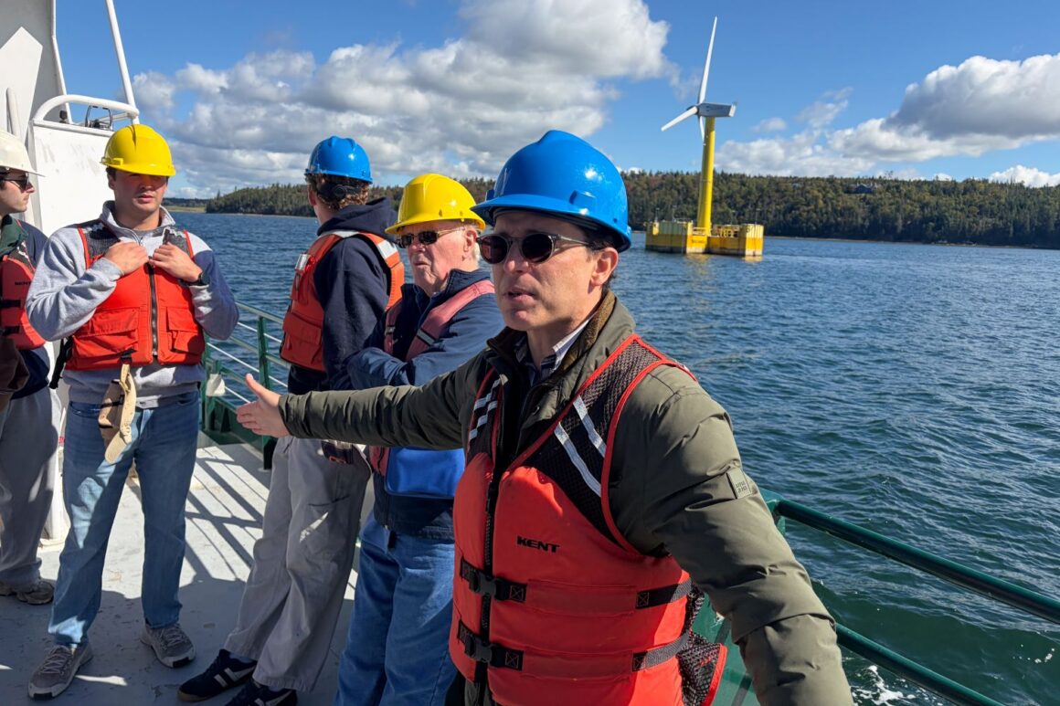 Anthony Viselli speaks to a group of people while standing on a boat