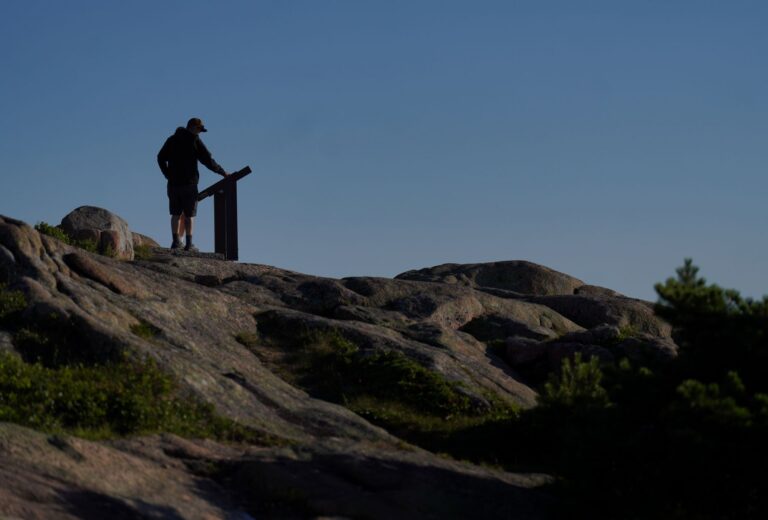 people reading a sign at the mountain's summit