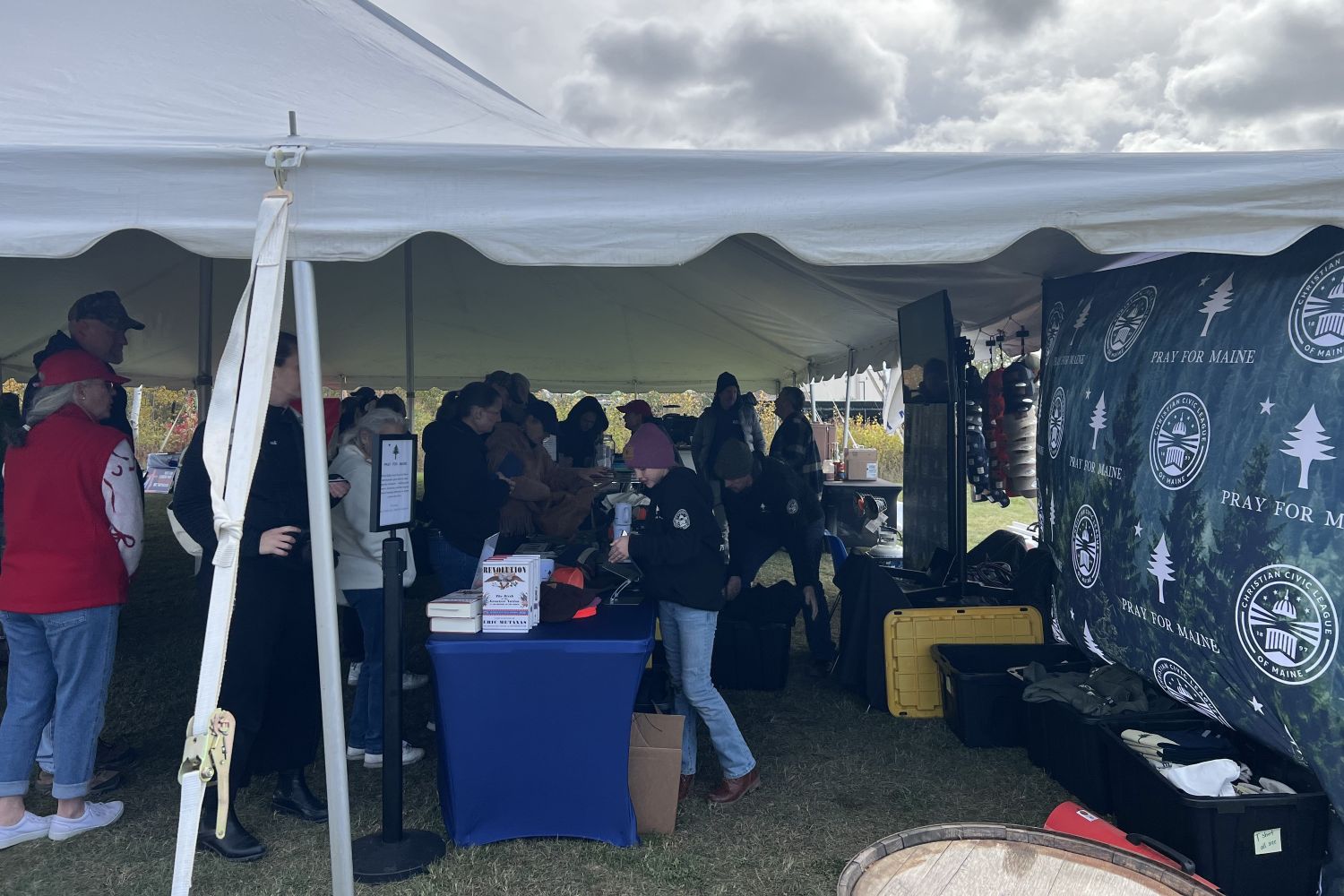 people standing in line under a tent to approach a table