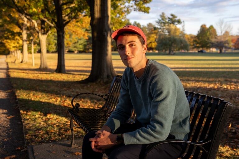 Jonathan Bisson poses for a photo while sitting on a park bench.