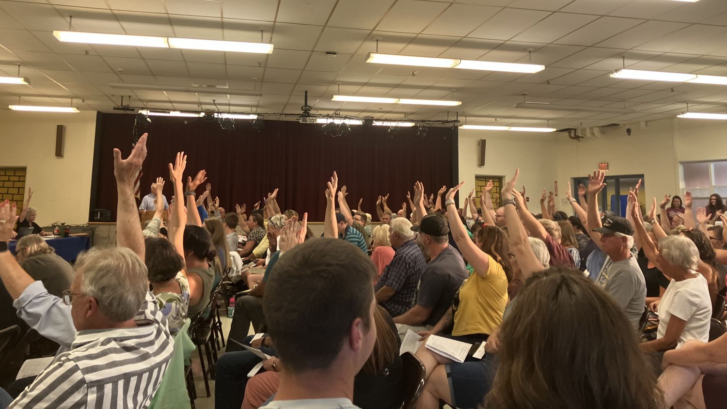voters raise their hands during a budget meeting.