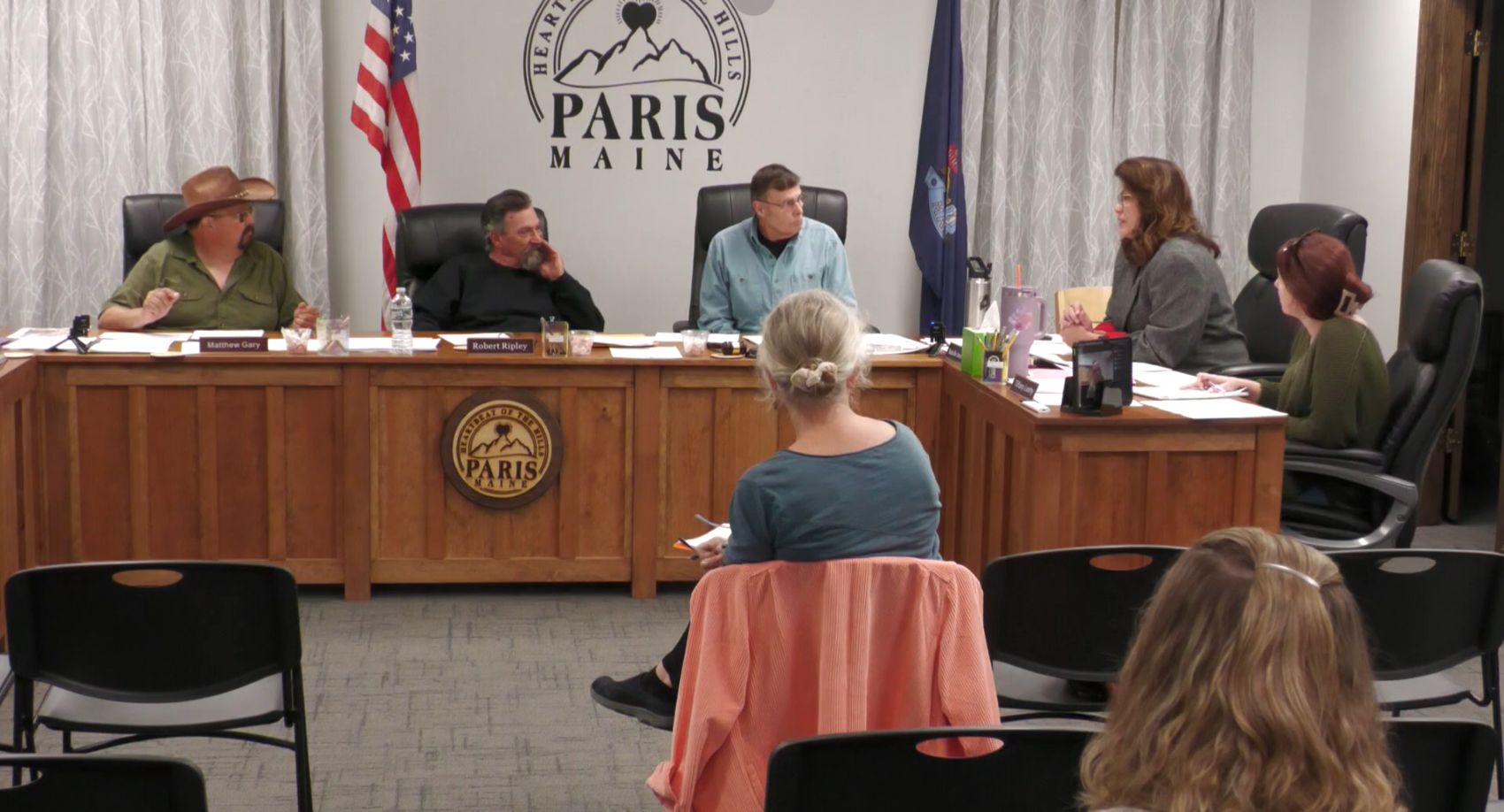 Members of the select board sit around a table during a meeting.