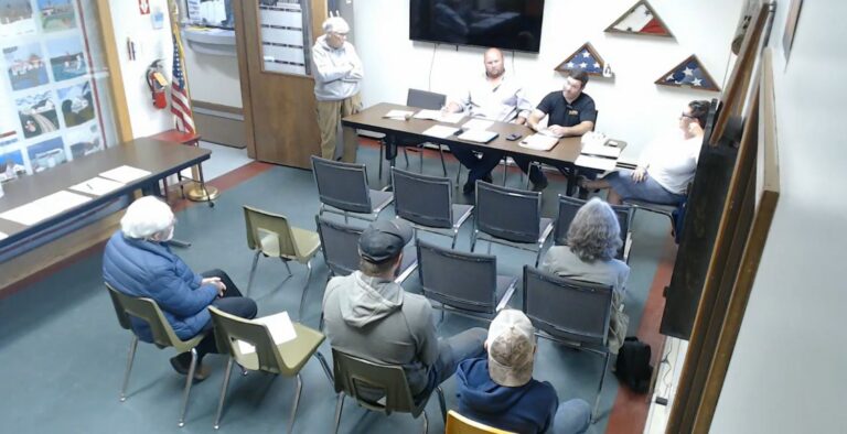 town officials and residents sitting in a small room during a meeting.