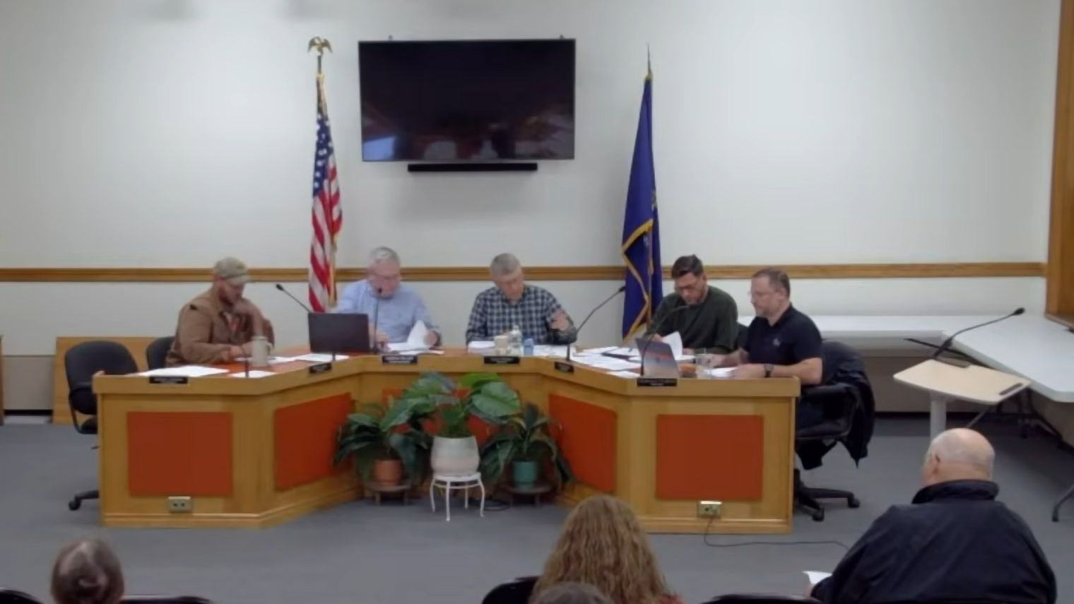 select board members sit around a table during a meeting.