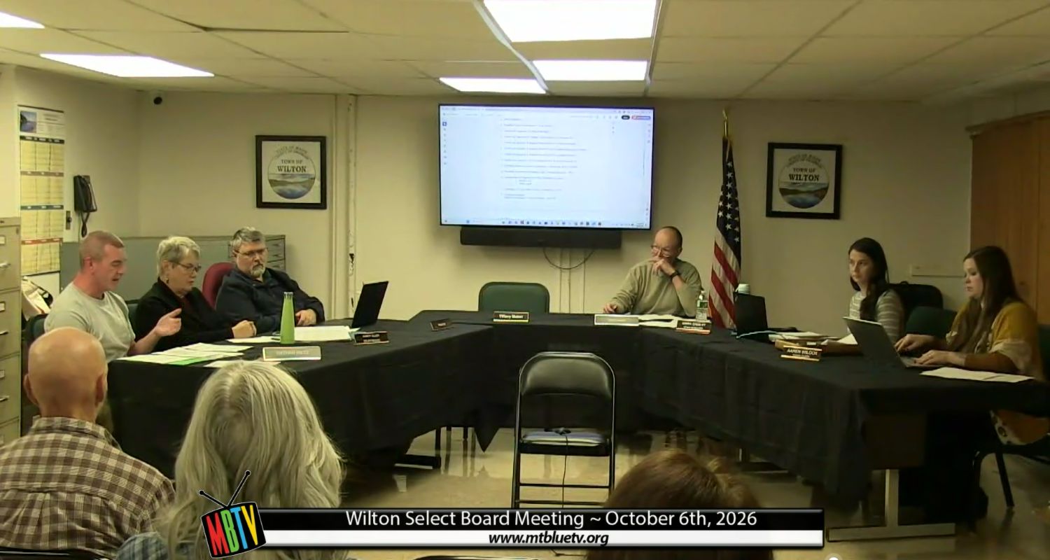 select board members sit around a v-shaped table layout